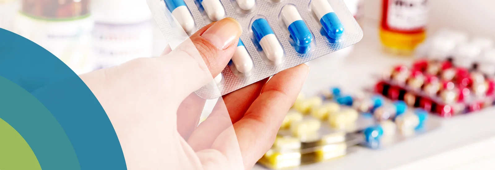 Hand holding a blister pack of blue and white capsules, from the original HMC website