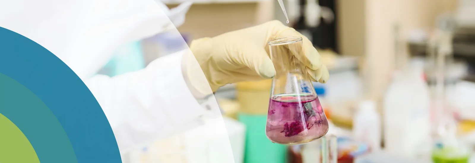 Gloved hand holding a flask of purple liquid below a dropper, from the original HMC website